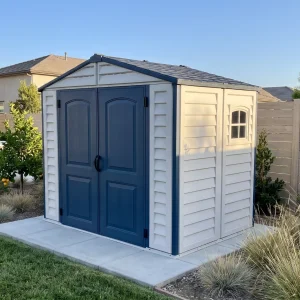 Duramax Ridgeline 8x6 vinyl storage shed in a landscaped residential backyard